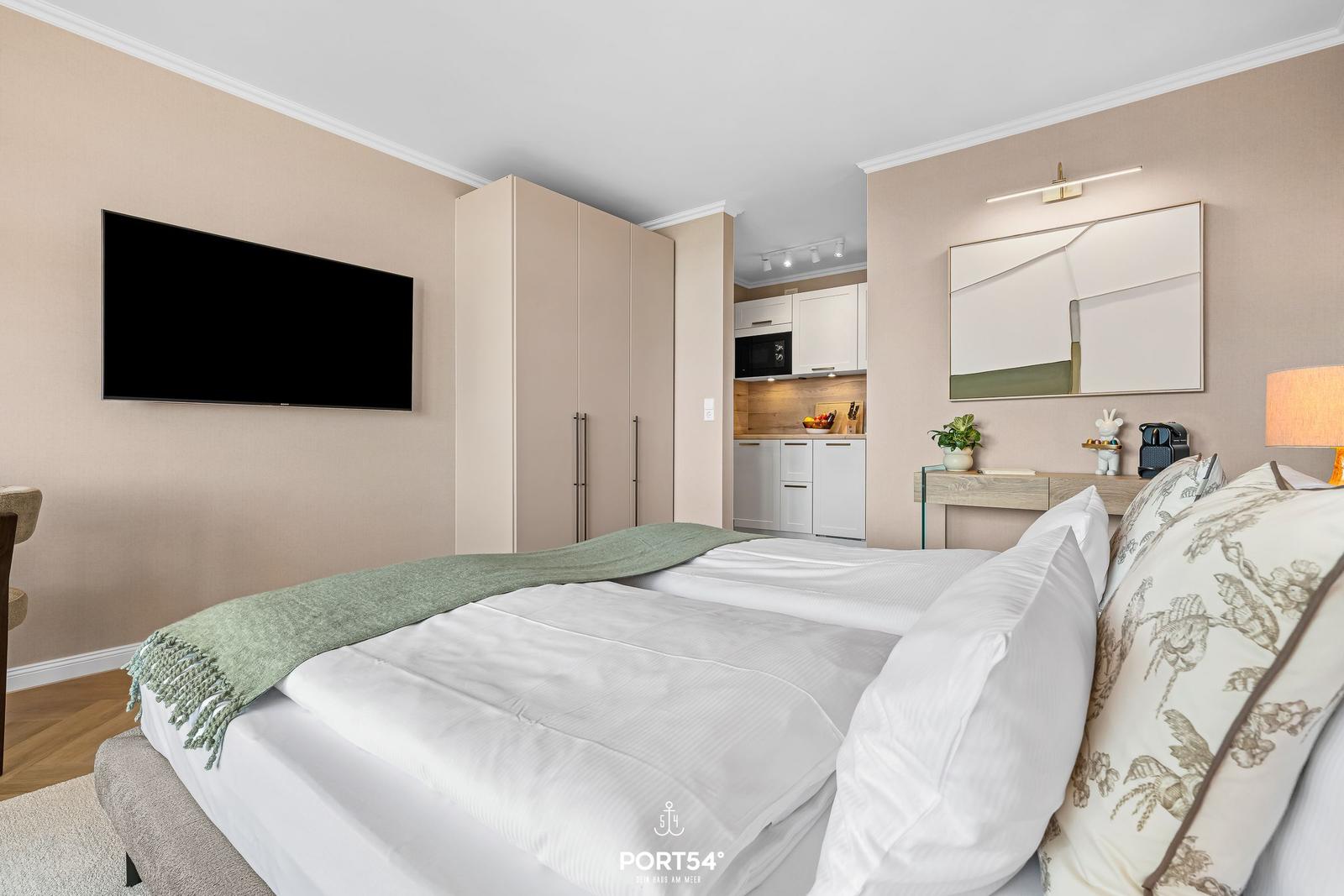 Bedroom with bed, TV, and adjacent kitchenette.