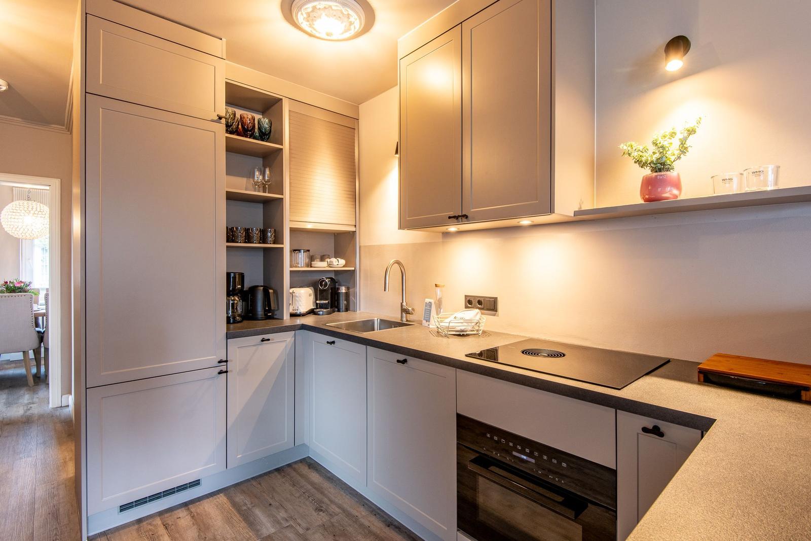 Modern kitchen with white cabinets, countertop, and built-in stove.