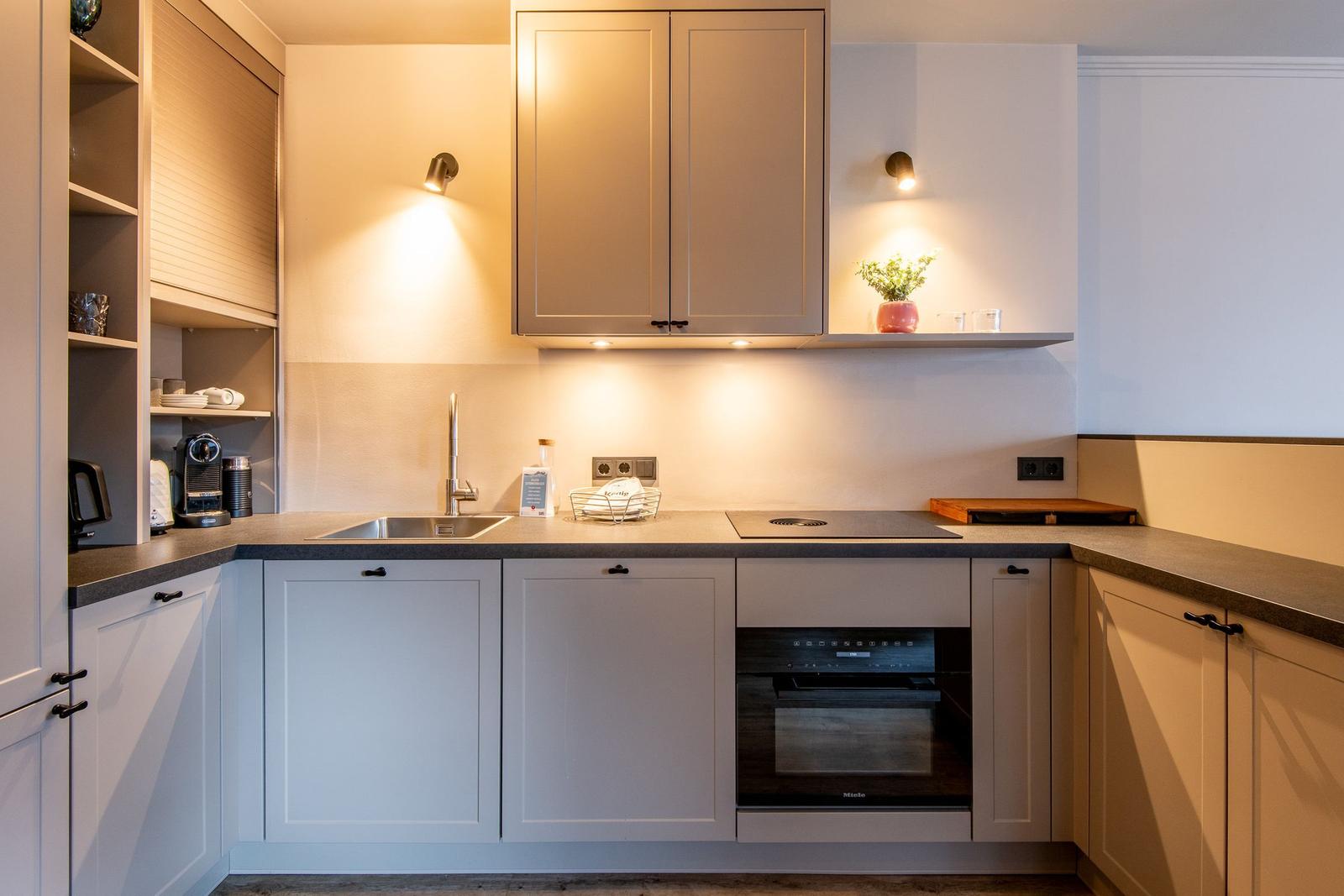 Kitchen with cabinets, sink, stove, and oven. A plant sits on a shelf.