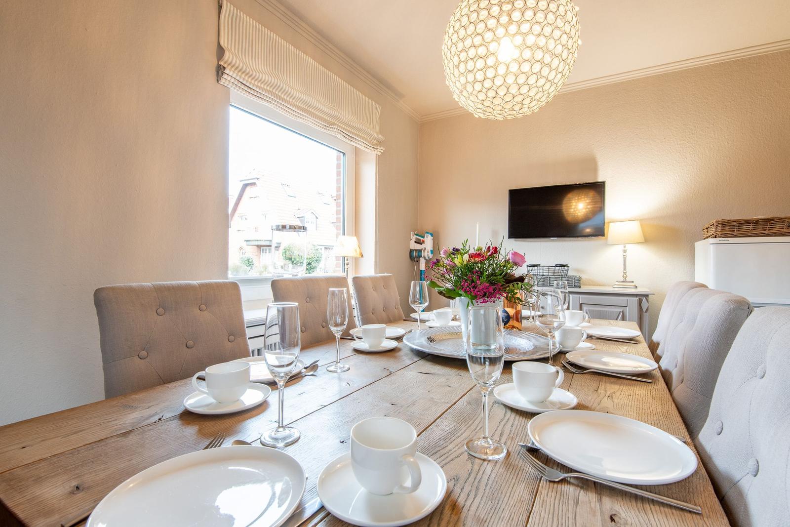 Wooden table with chairs, window and TV in dining room.