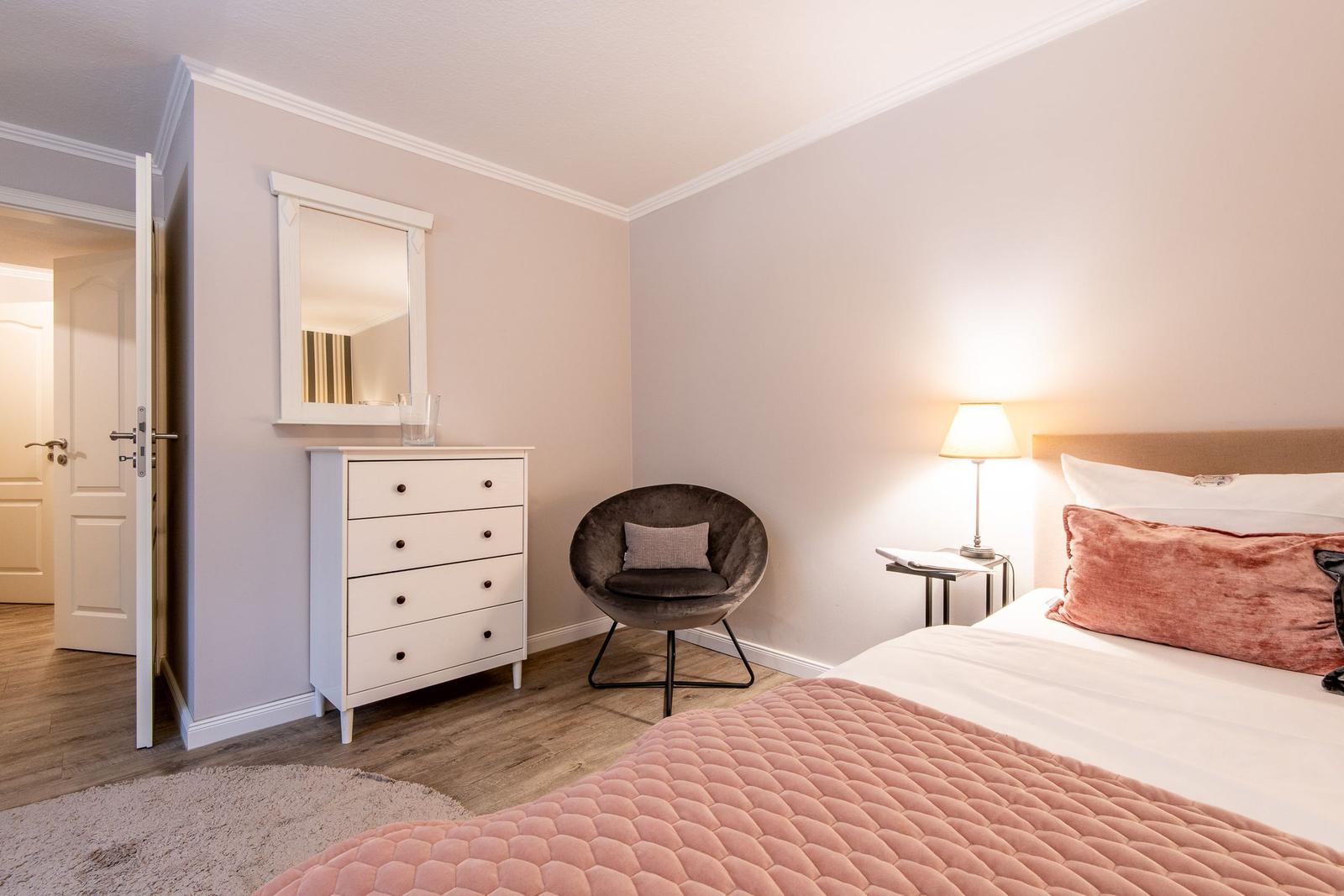 Bedroom with bed, nightstand, lamp, chair, and dresser.