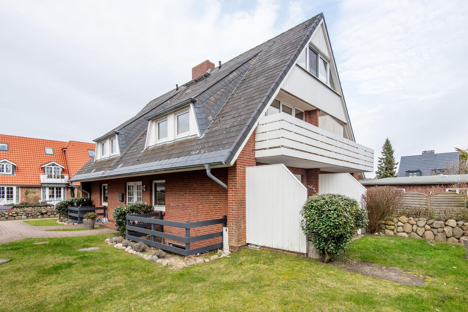 House with balcony, garden, and tiled roof. Modern design with wooden and stone cladding.