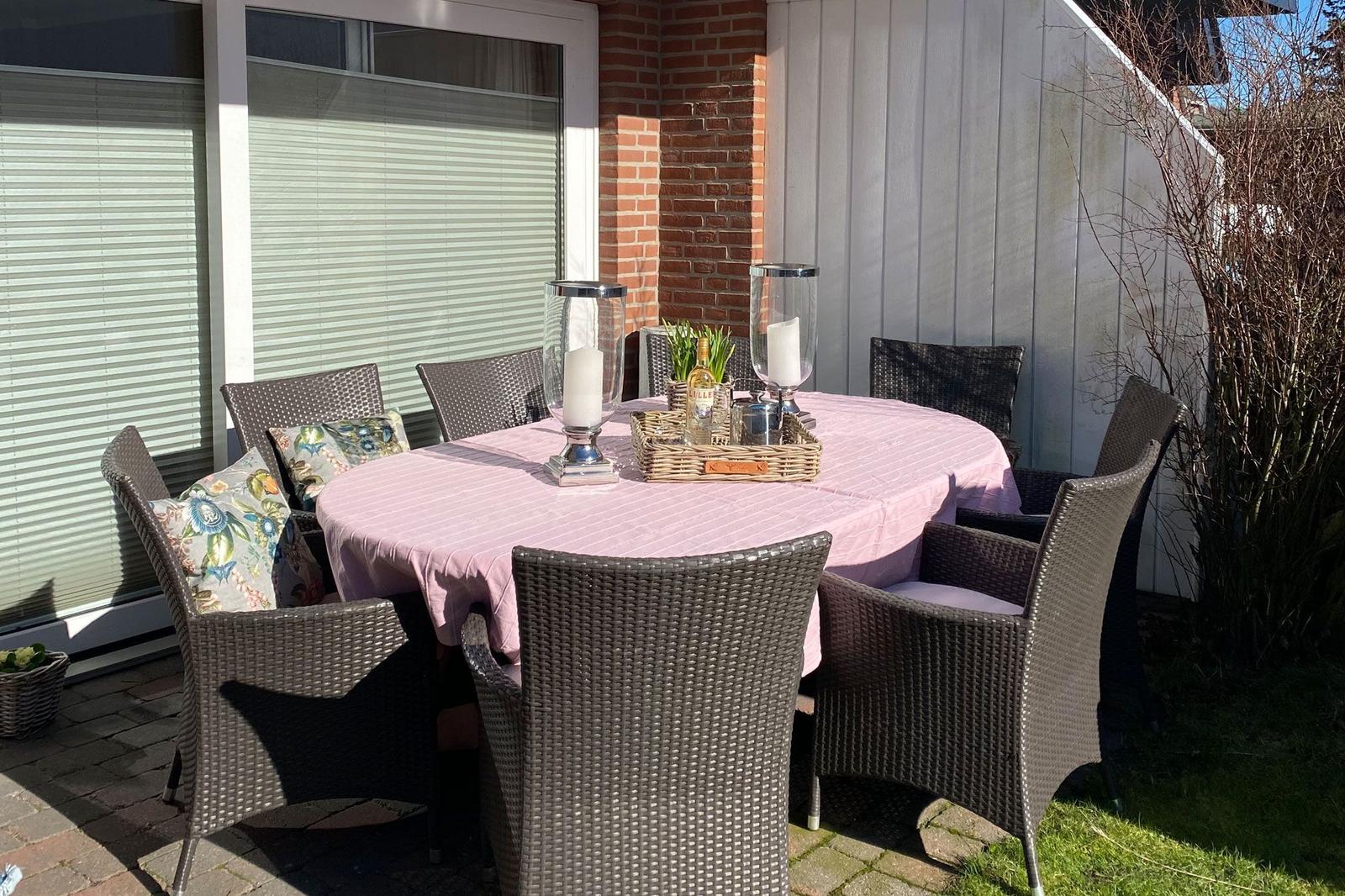 Round table with chairs, tablecloth, and candles on terrace.