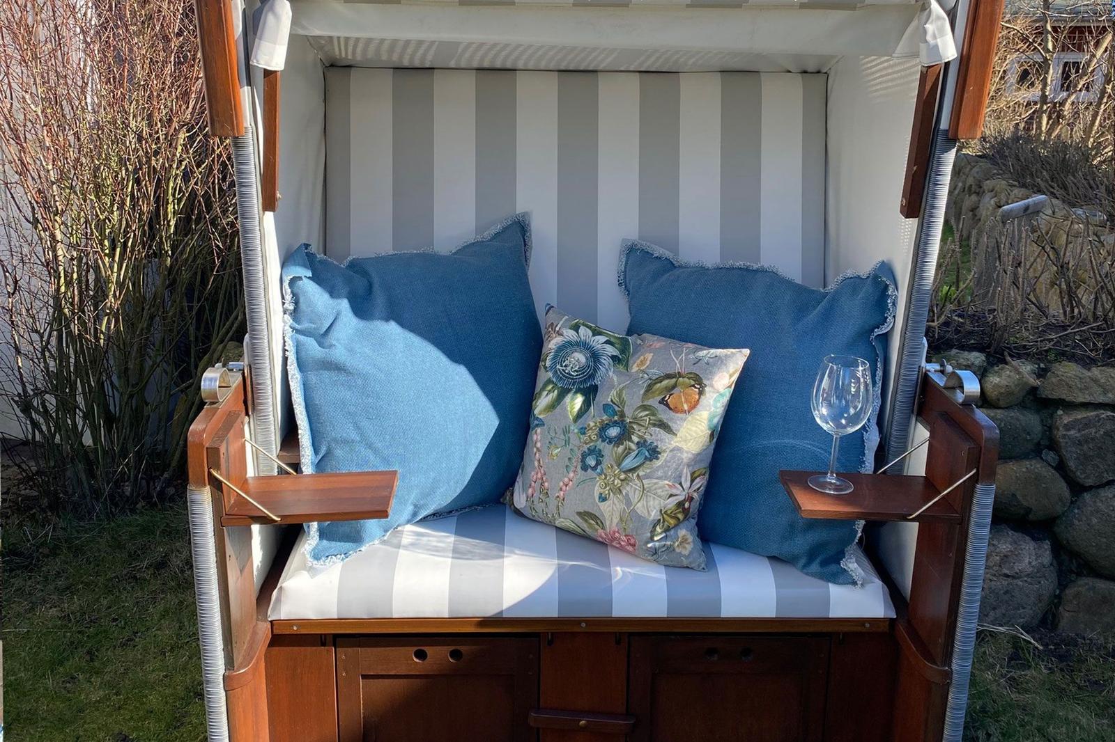 Cushion with blue pillows and floral embroidery. White glass on armrest.