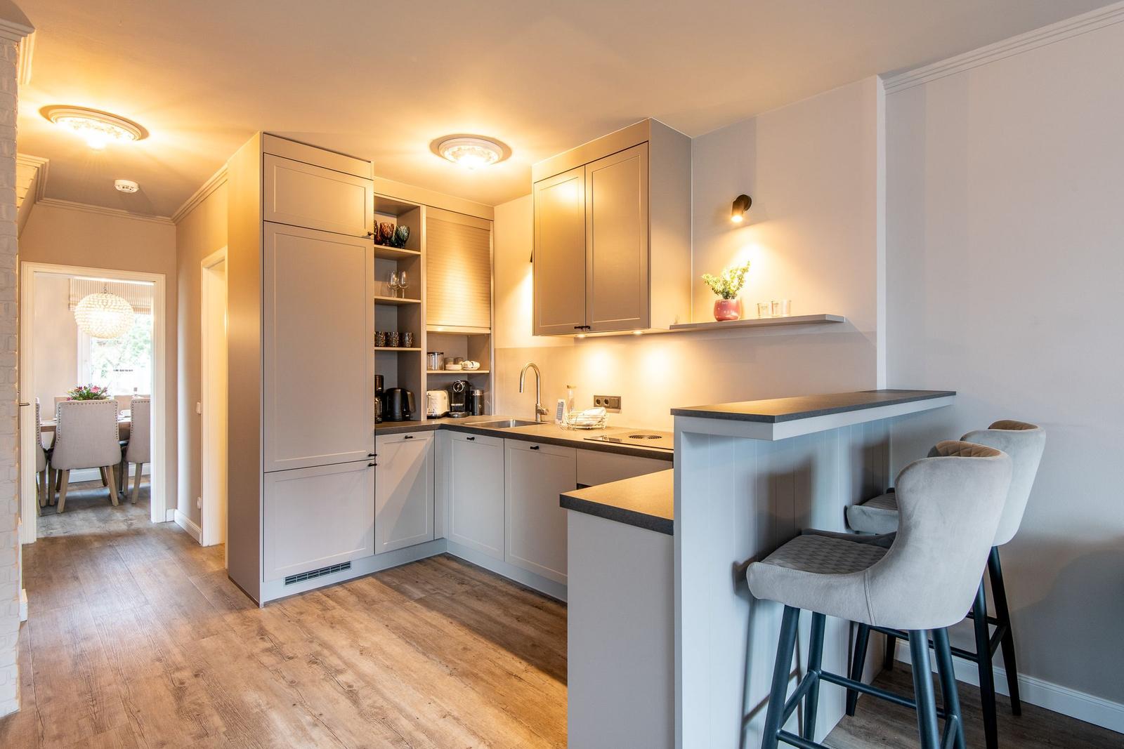 Modern kitchen with countertop and bar stools. View into dining room.