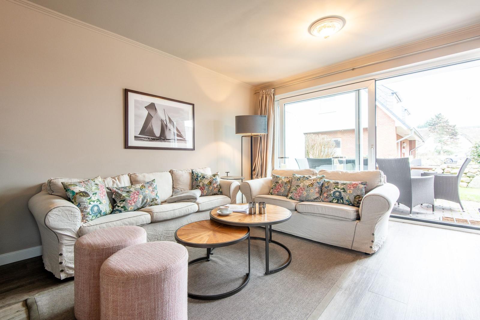Living room with two sofas, round tables, and view to the terrace.