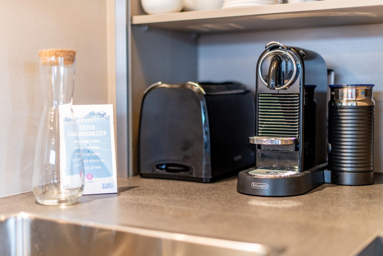 Kaffeemaschine, Toaster und Wasserglas auf Küchenarbeitsfläche