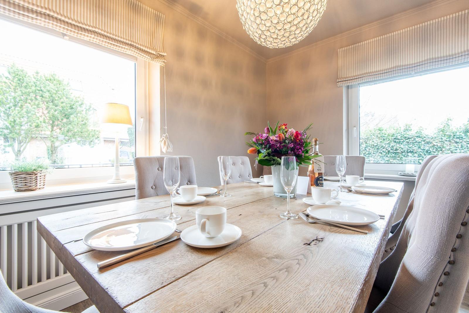 Esszimmer mit Holztisch, Stühlen und Blumendekoration.