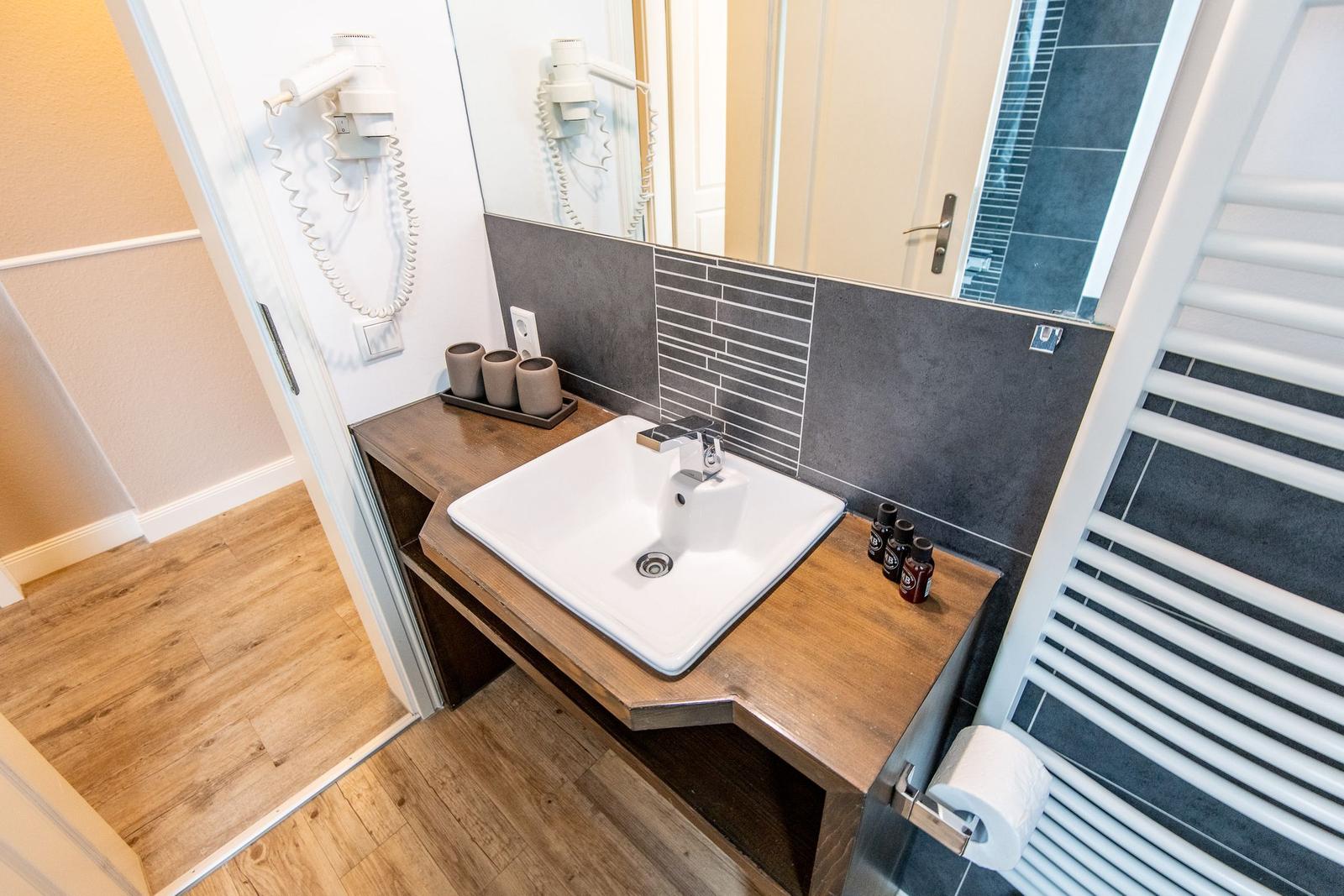 Waschbecken mit Spiegel, Handtuchwärmer und Toilettenpapier