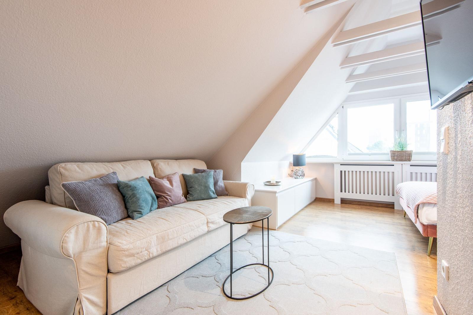 Wohnbereich mit Sofa, Tisch und Fenster unter Dachschräge