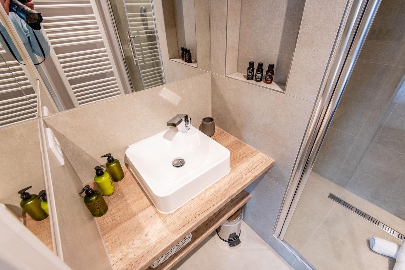 Badezimmer mit Waschbecken, Dusche und Flaschen