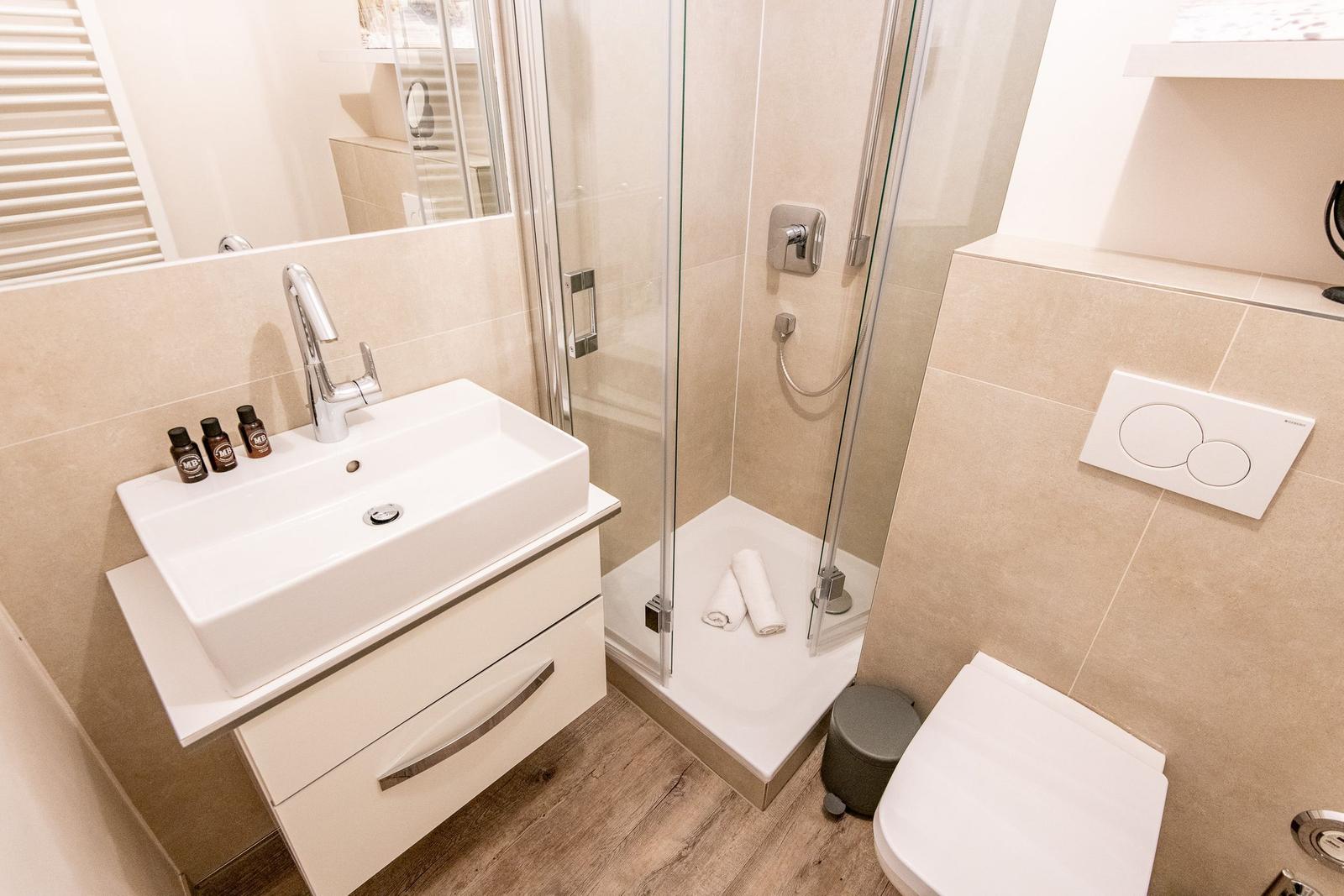Badezimmer mit Dusche, Waschbecken und Toilette.