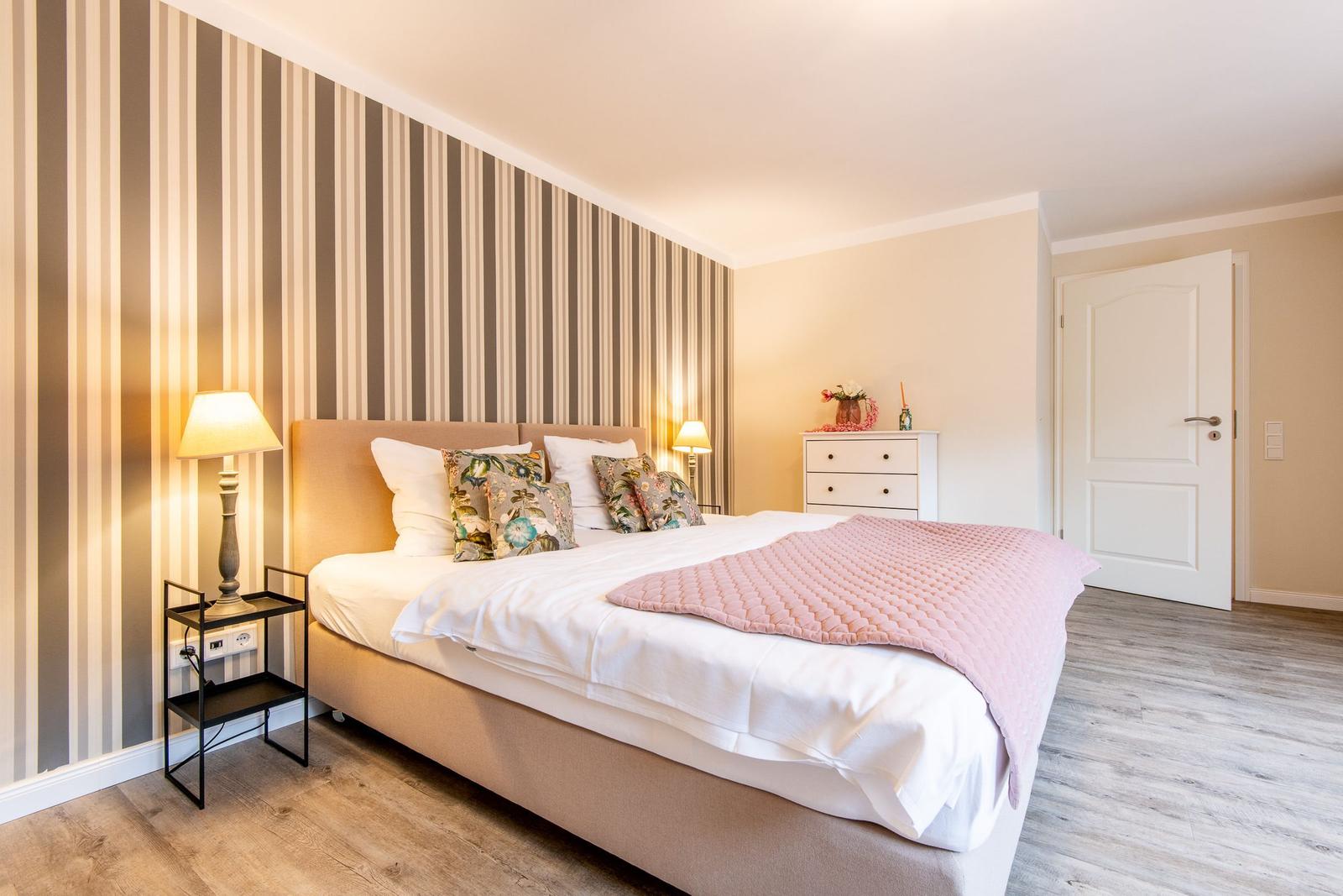 Schlafzimmer mit Bett, Nachttisch und Schrank an der Wand mit Streifen.