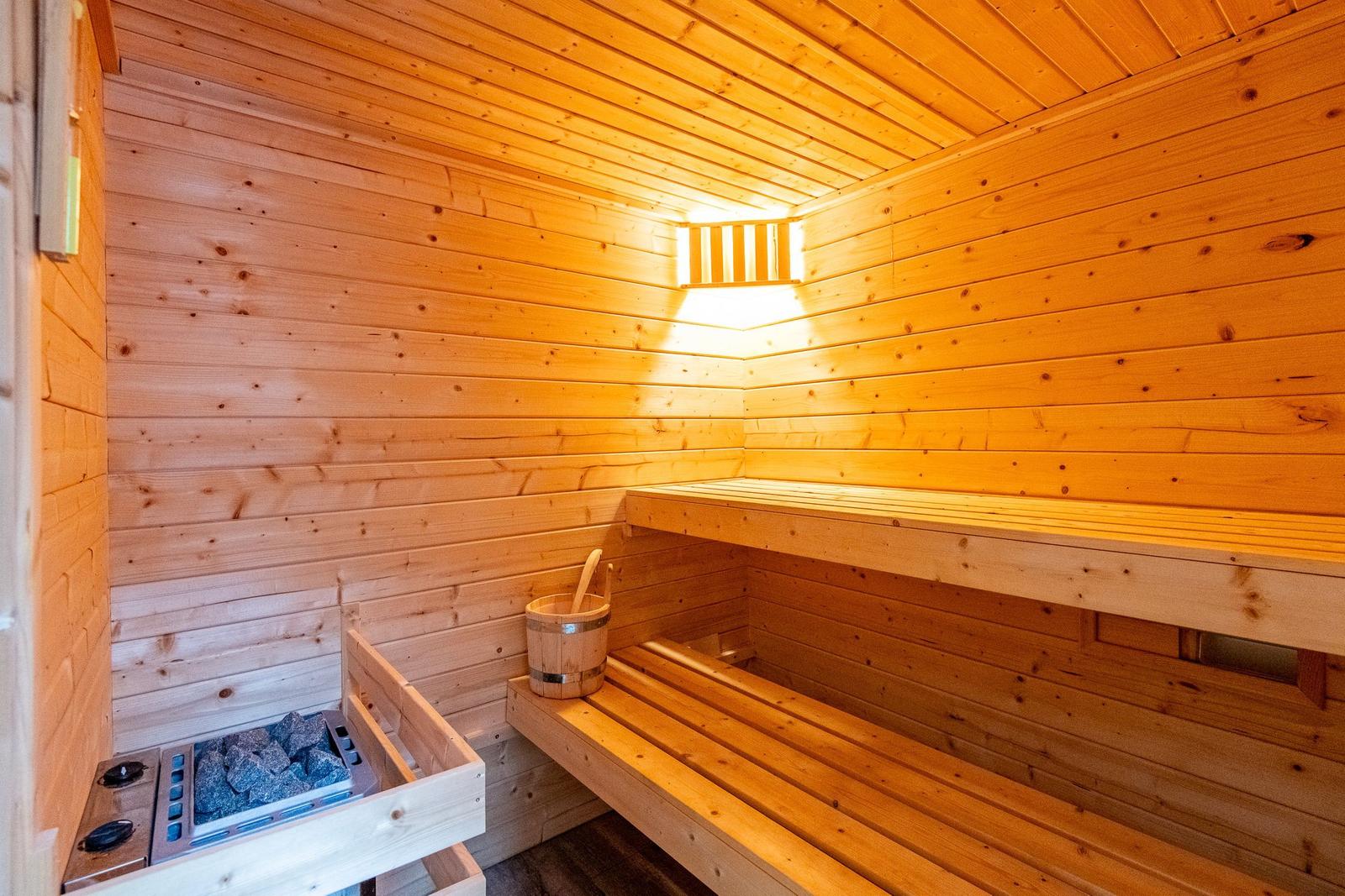 Sauna mit Holzbank, Steinofen und Eimer