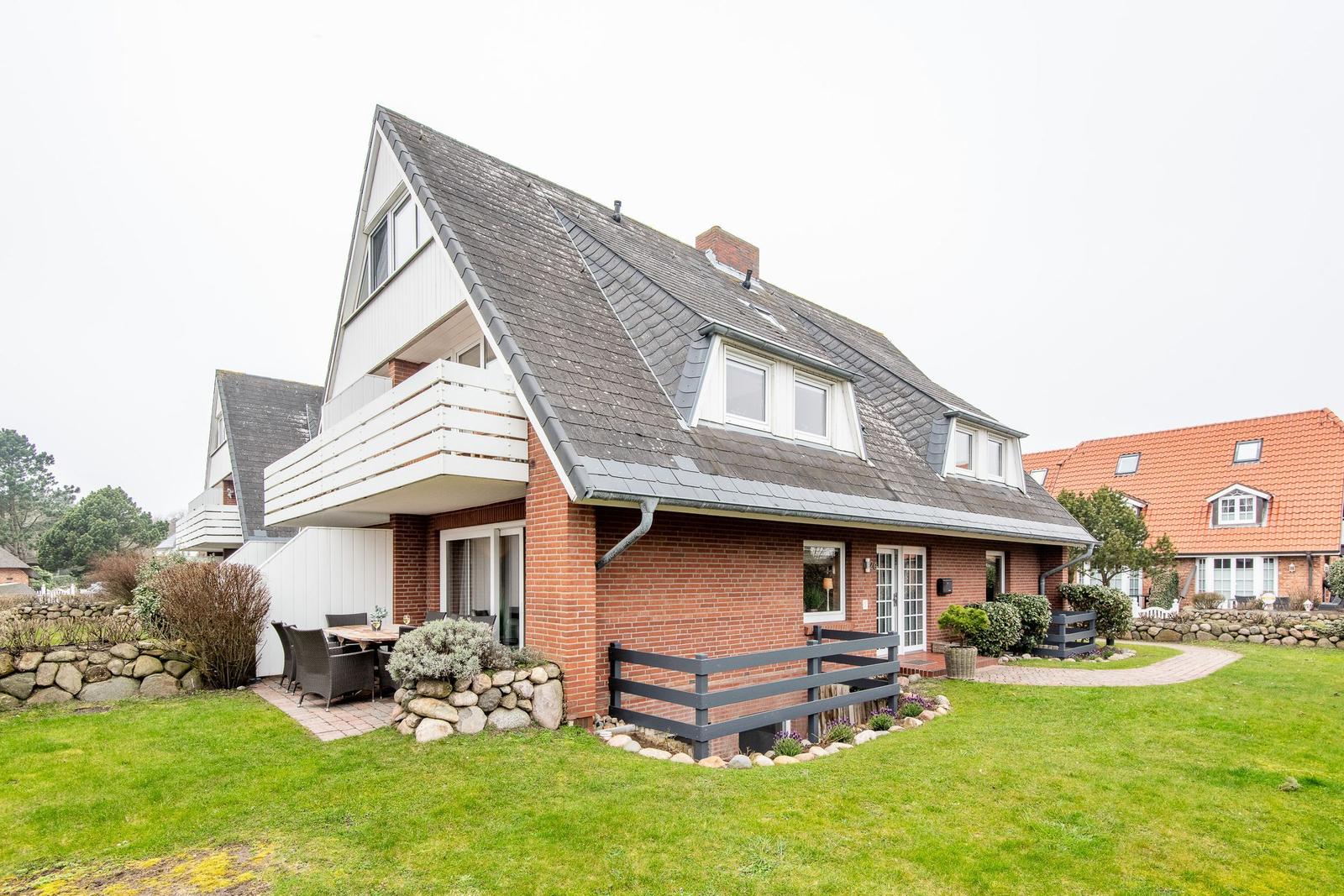 Ferienhaus mit Balkon, Garten und Terrasse. Modernes Design mit Steinmauern und Pflanzen.