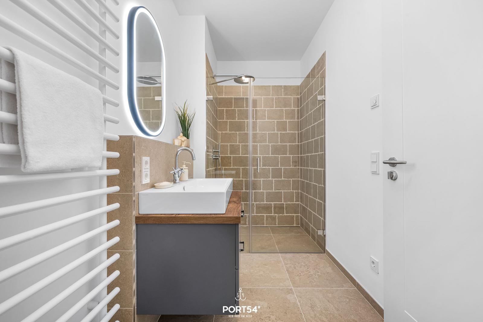 Bathroom with shower, sink, and heated towel rack.