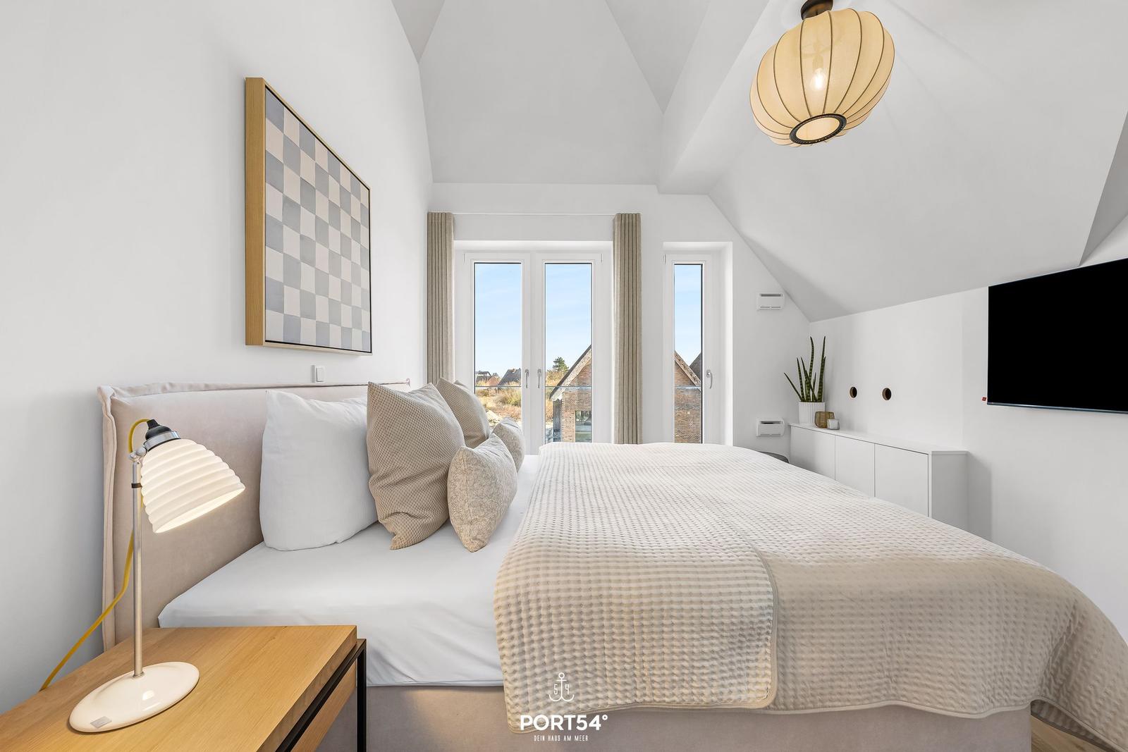 Bedroom with bed, windows, and ceiling lamp.