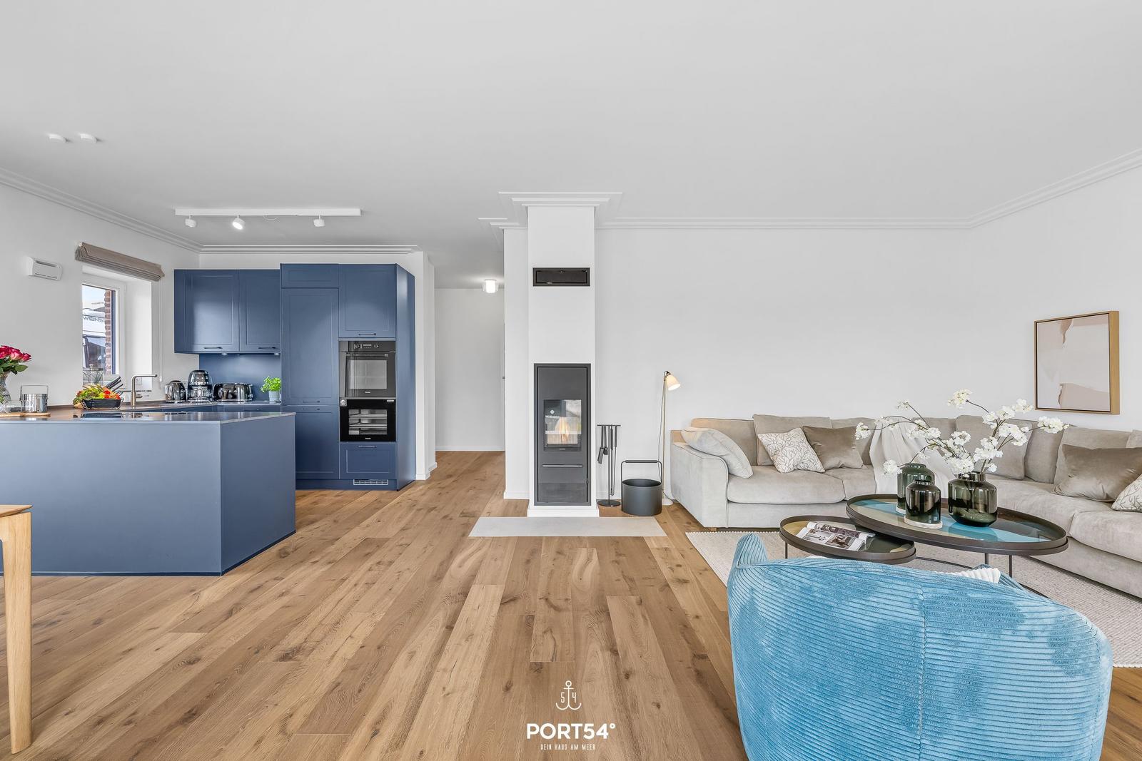 Modern kitchen with blue cabinets and living room with sofa and fireplace.