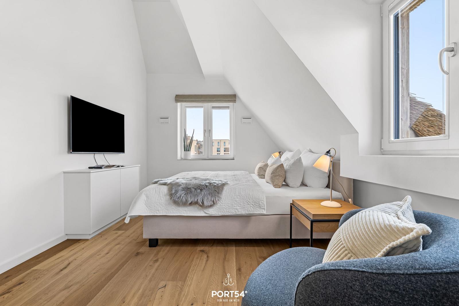 Schlafzimmer mit Dachschräge, Bett, Fernseher und Fenster