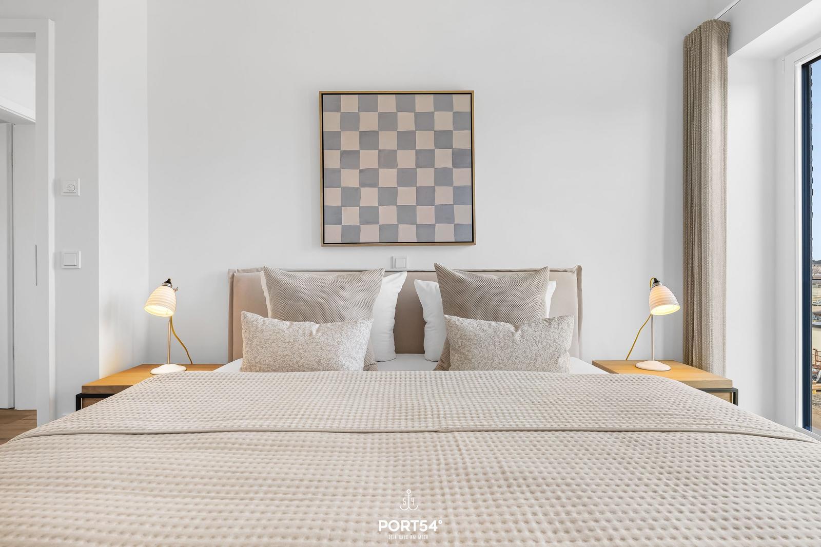 Schlafzimmer mit Bett, Nachttischen und Wandbild.