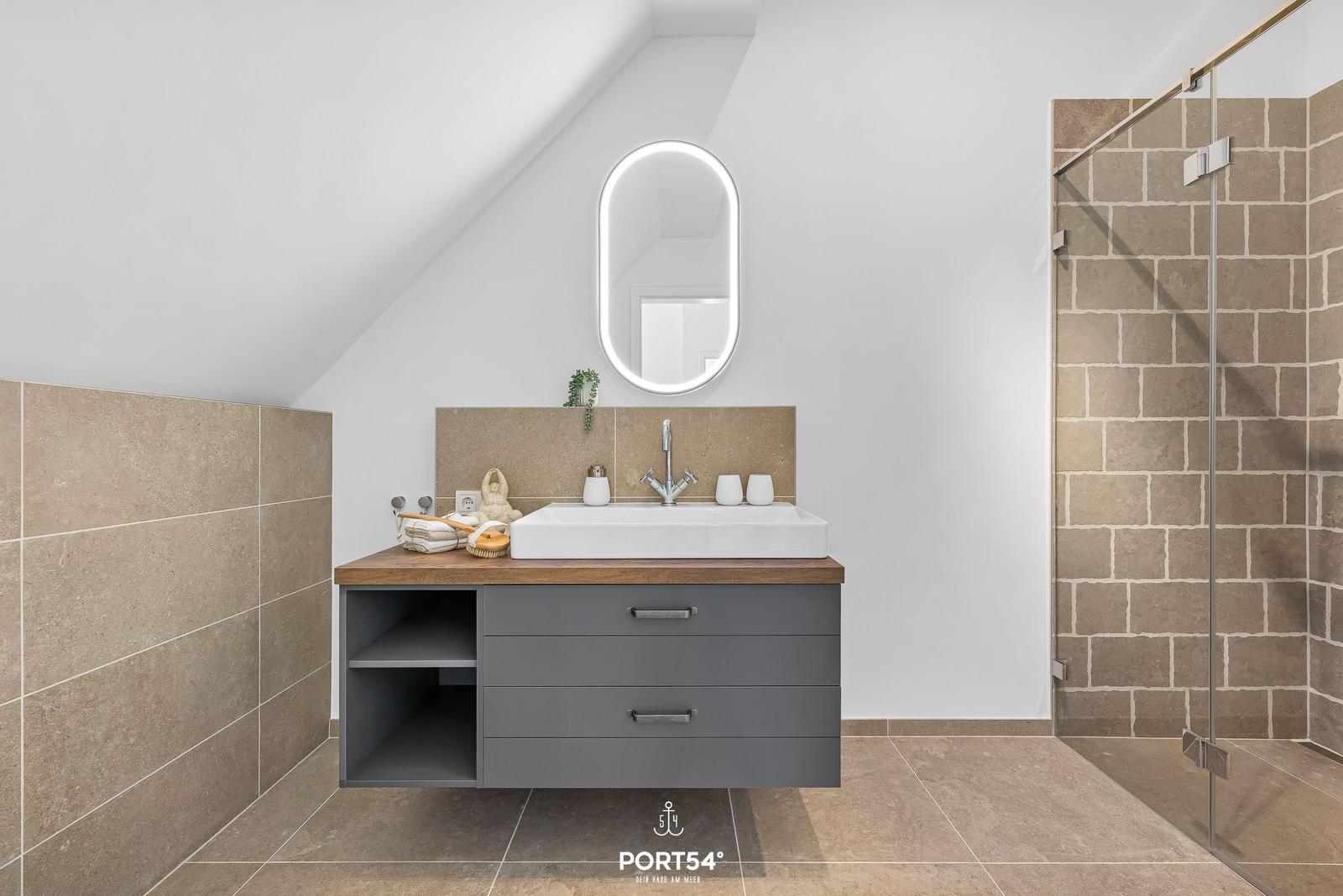 Badezimmer mit Dusche, Waschbecken und Spiegel unter Dachschräge