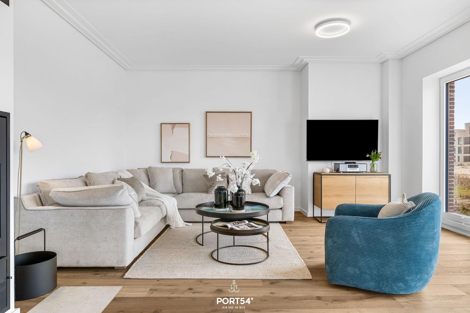 Wohnzimmer mit Sofa, Sessel, Couchtisch und Fernseher.
