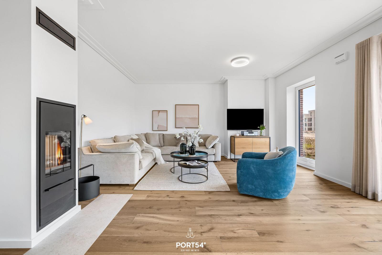 Wohnzimmer mit Kamin, Sofa, TV und blauem Sessel.