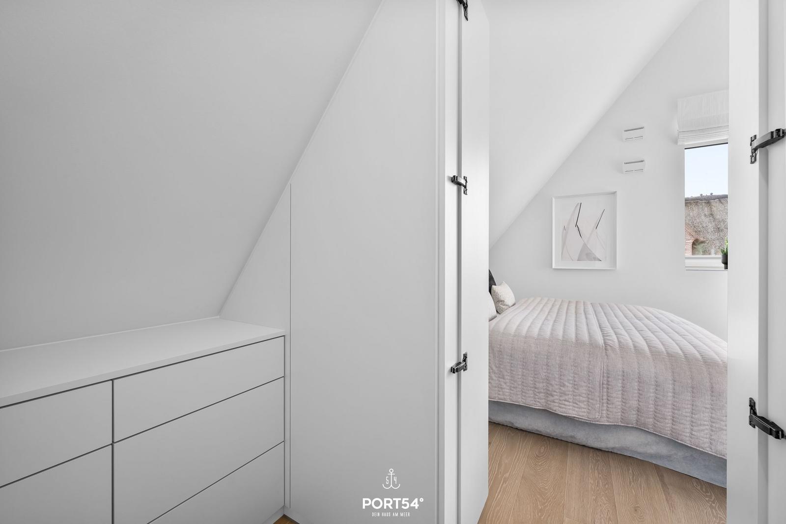 Bedroom with sloped ceiling, bed, and dresser