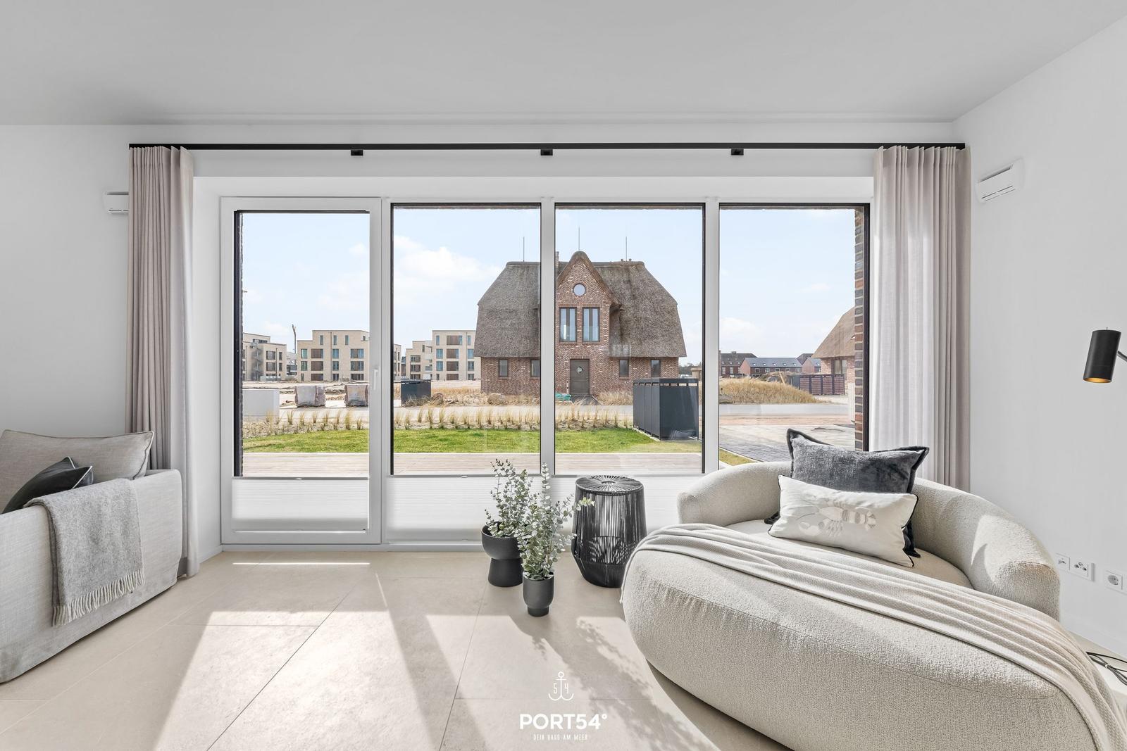 Living room with large window view of rooftops and green areas.