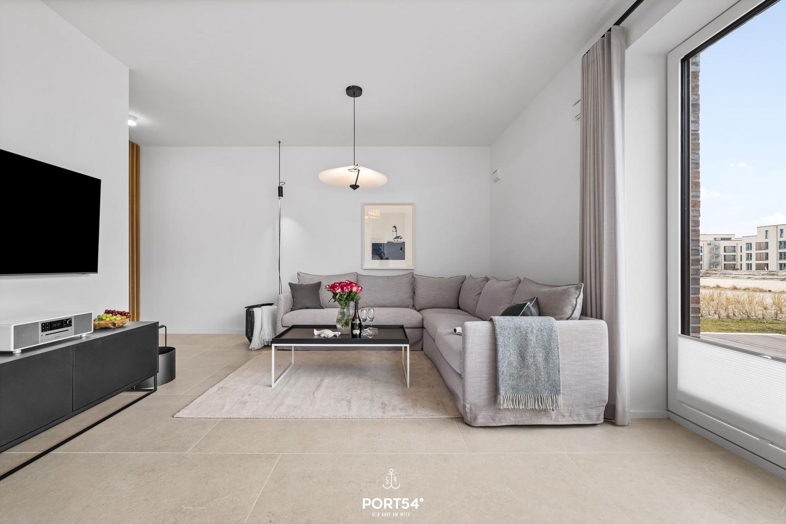 Living room with corner sofa, TV, and large window.