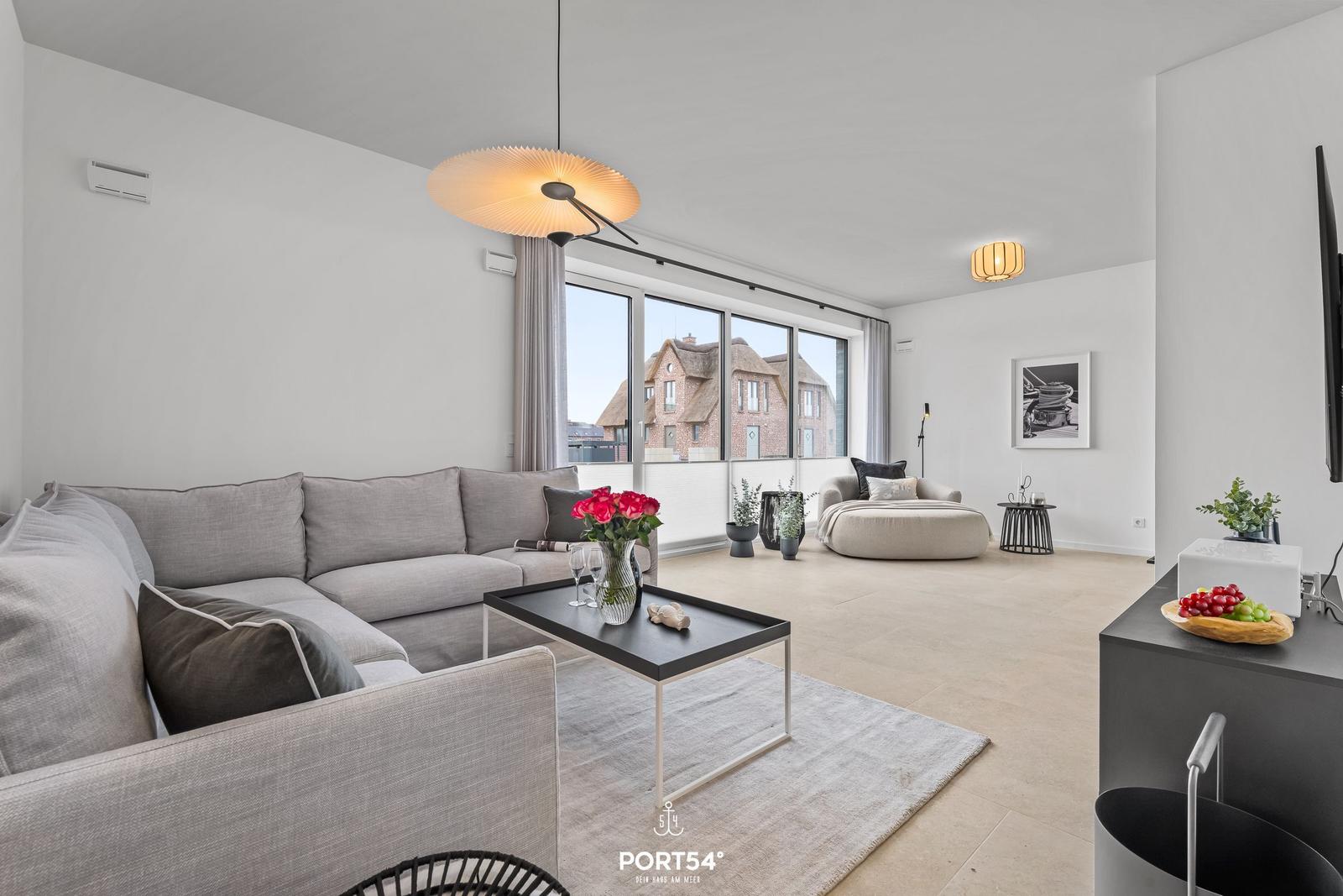 Living room with sofa, coffee table, and view of rooftops.