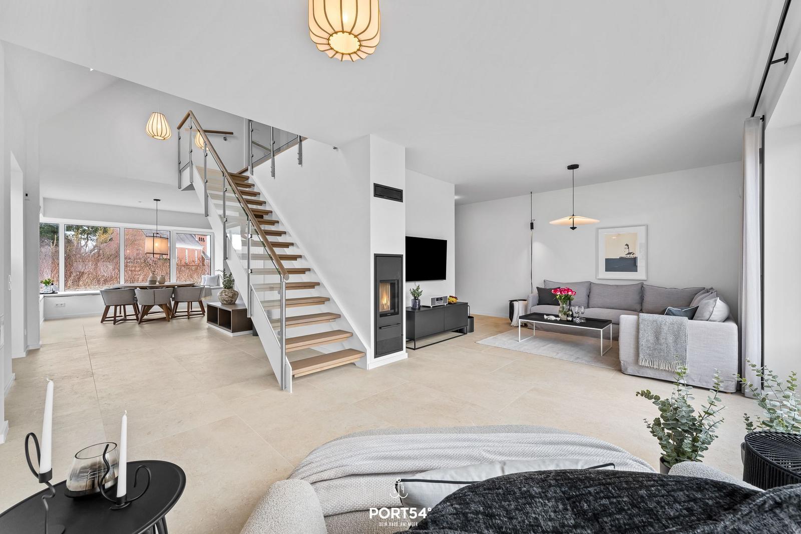Living area with sofa, TV, and fireplace. Stairs lead to dining room with table and chairs.
