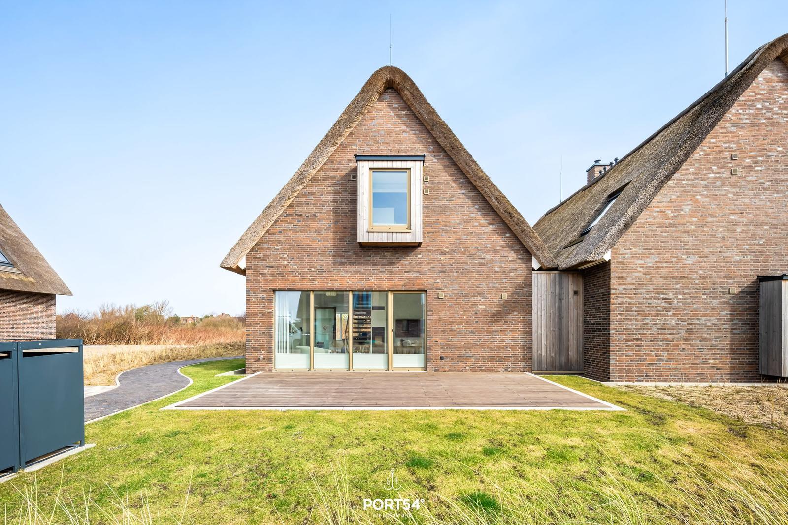 House with thatched roof and glass facade