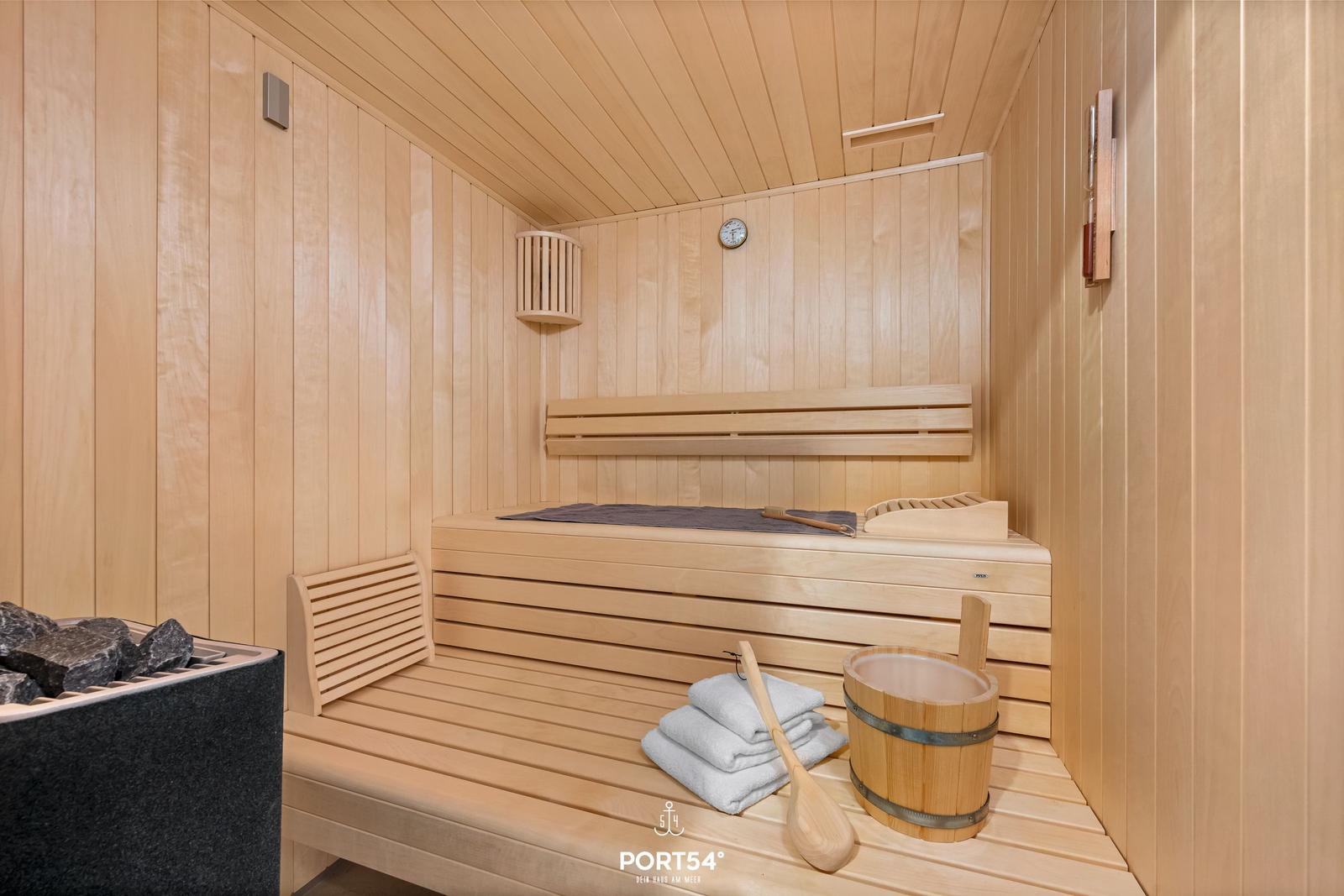 Sauna mit Holzbank, Waschbecken und Handtuch.