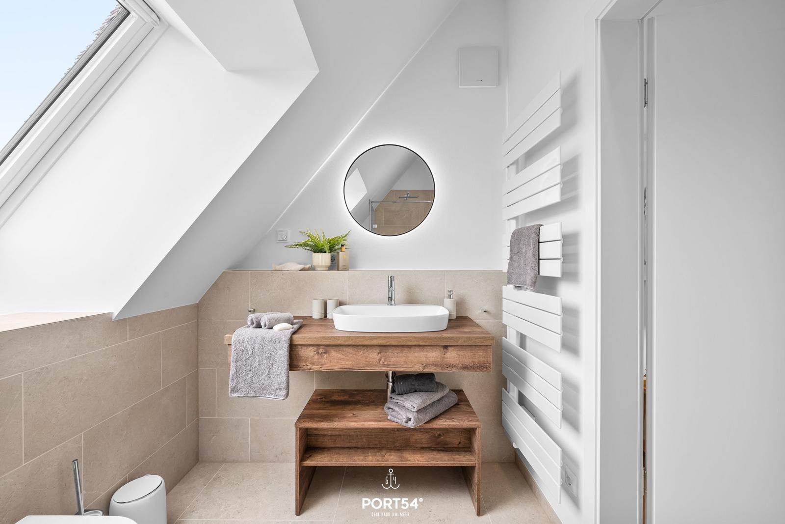 Badezimmer mit Dachschräge, Waschtisch und Heizungswand.