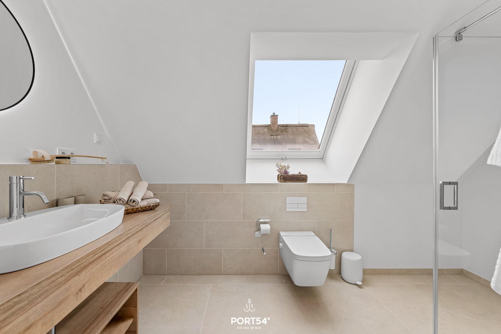 Badezimmer mit Dachfenster, Waschtisch und Dusche.