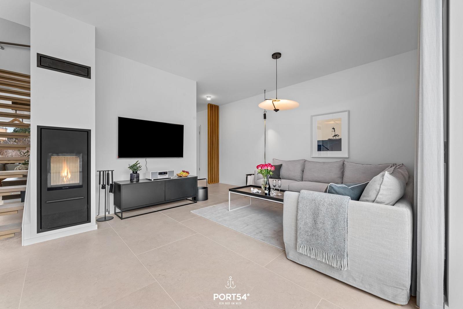 Wohnzimmer mit Sofa, Kamin und Fernseher.