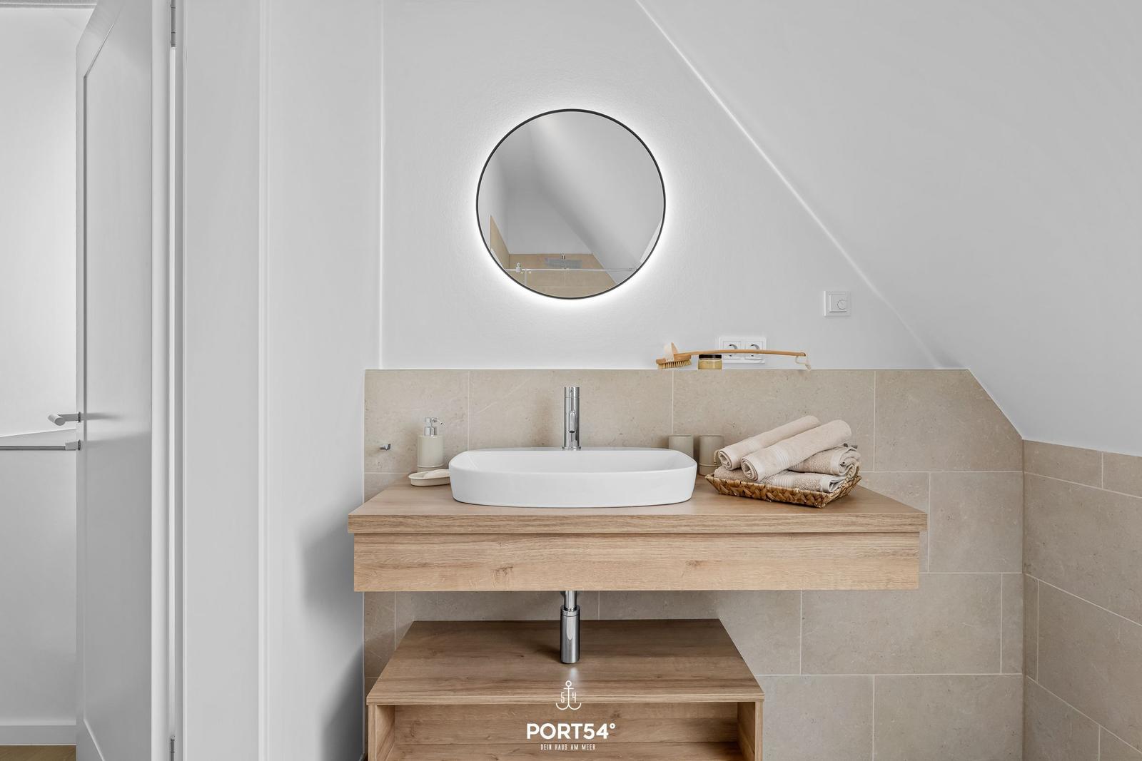Waschbecken mit Spiegel und Handtüchern in Dachschrägen-Badezimmer