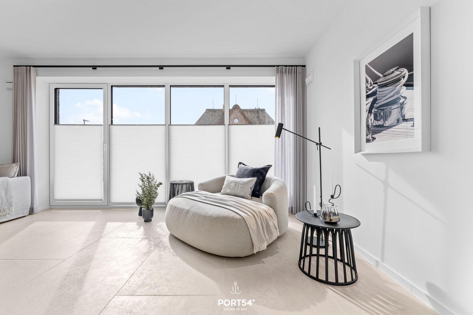 Wohnraum mit Sessel, Tisch und Fenster zur Aussicht.