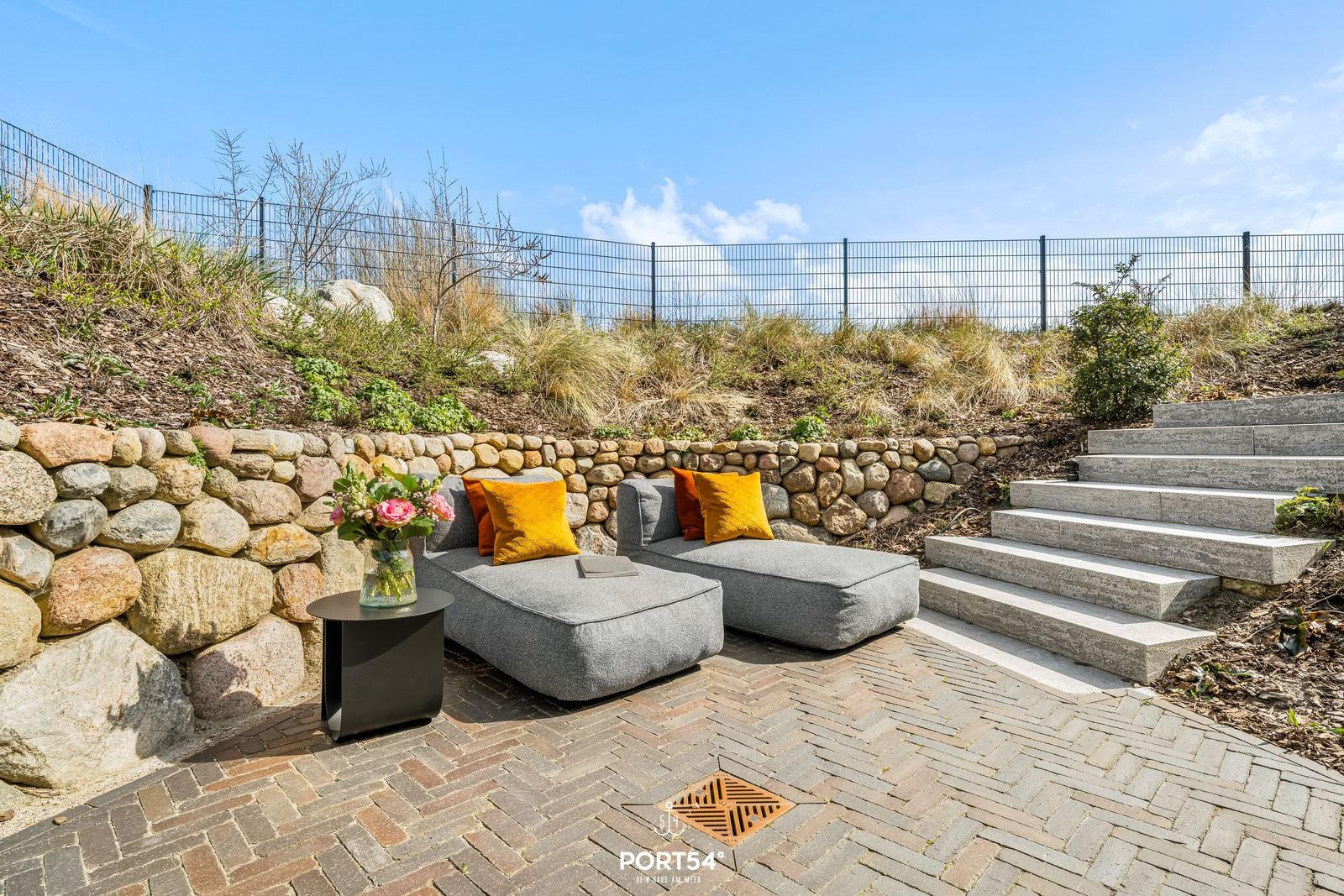 Outdoor area with gray sofa, yellow cushions, and stone stairs.
