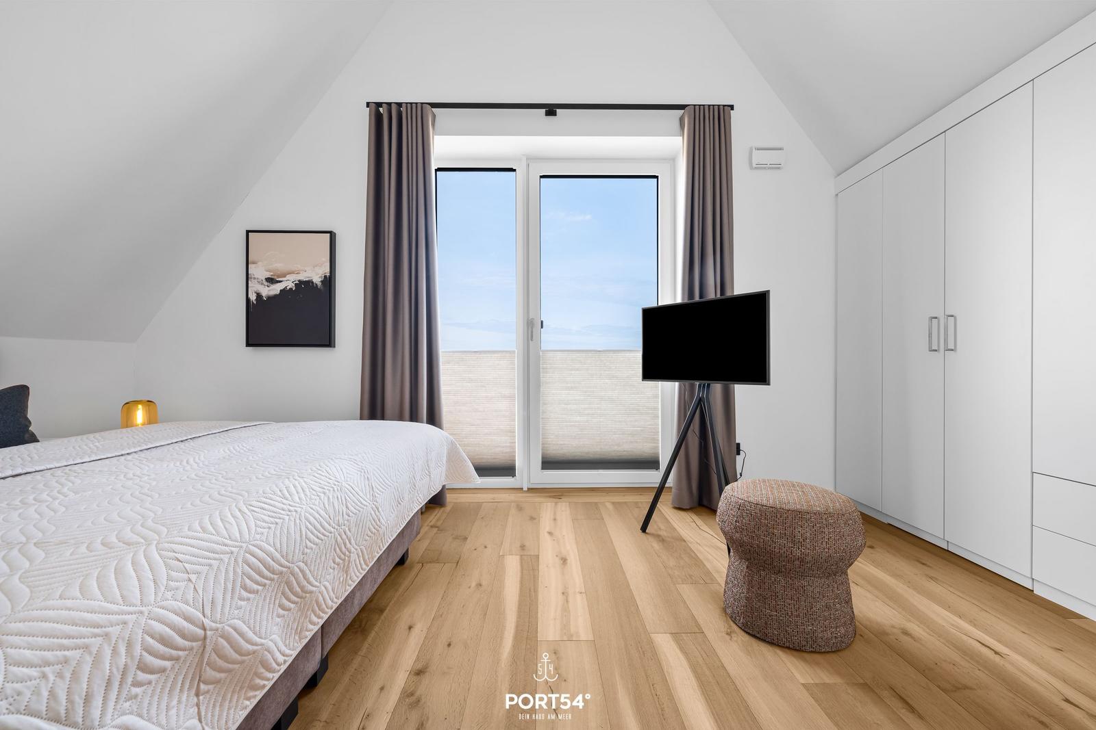 Bedroom with bed, TV, and balcony view.