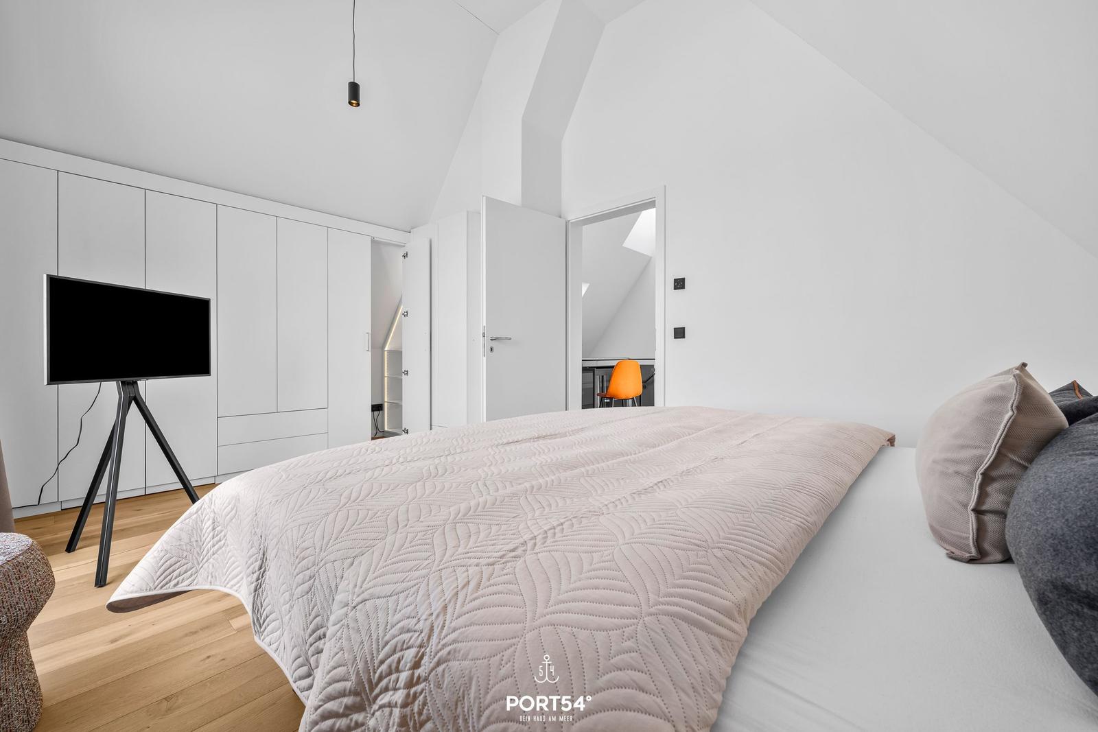 Bedroom with bed, TV, and sloped ceiling