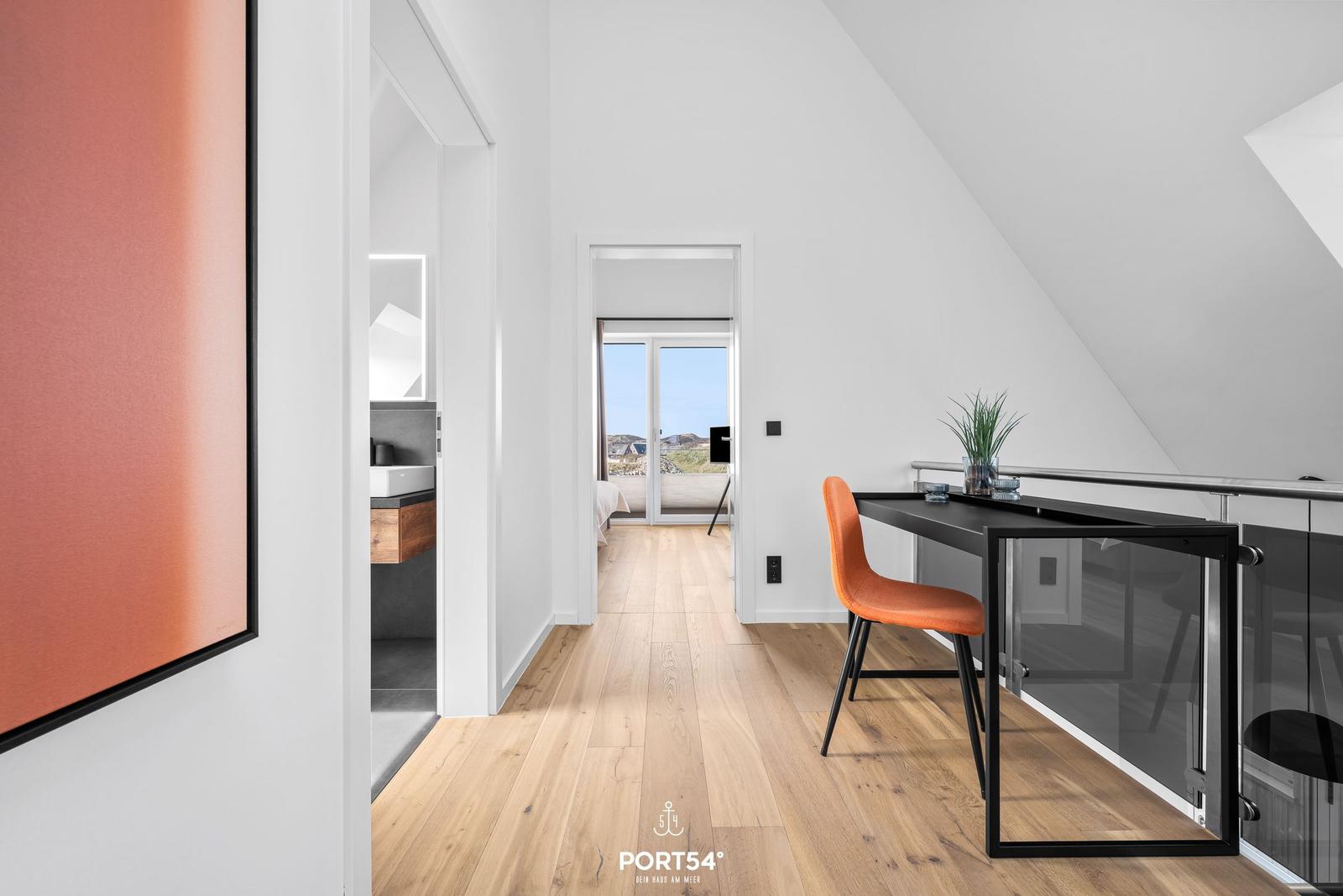 Bedroom with sea view and work desk with orange chair.
