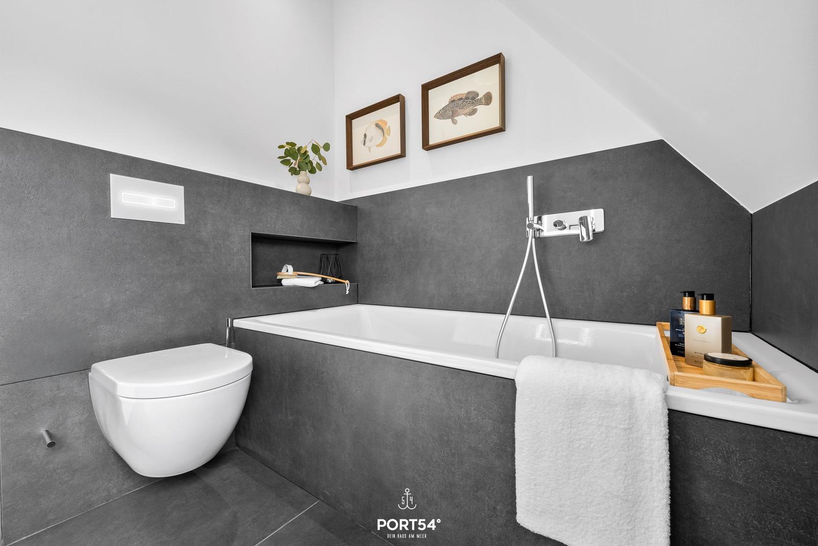 Bathroom with bathtub, toilet, and wall pictures
