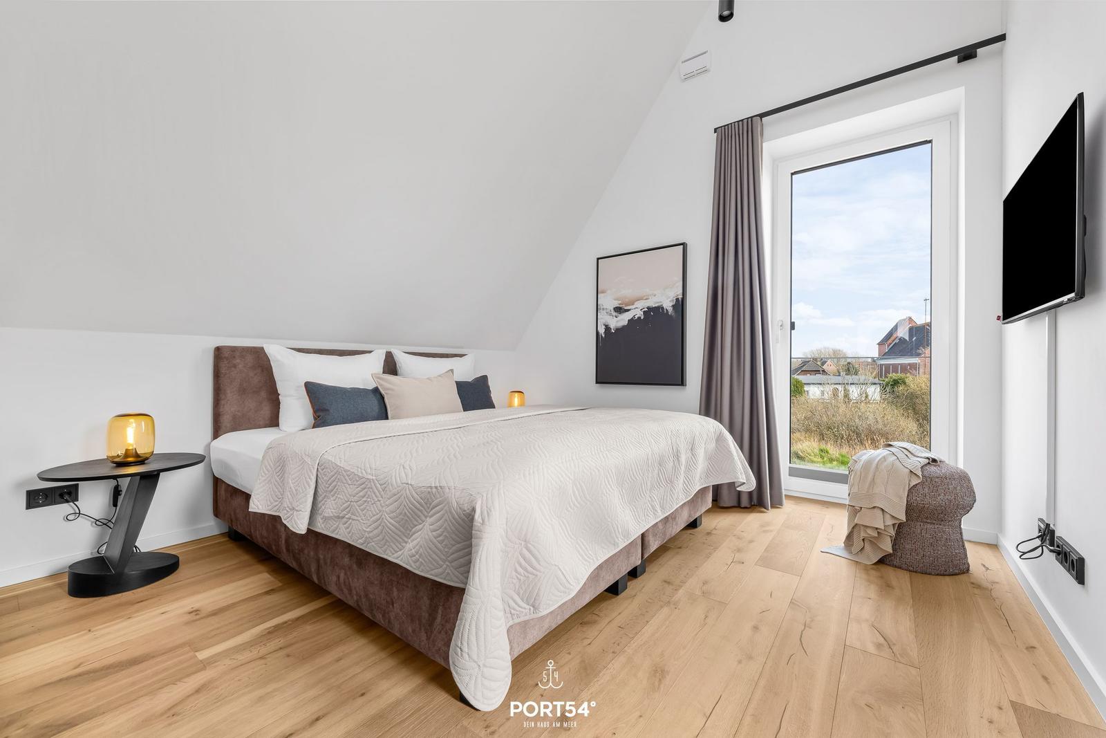 Bedroom with double bed, wooden floor, and large window with view.