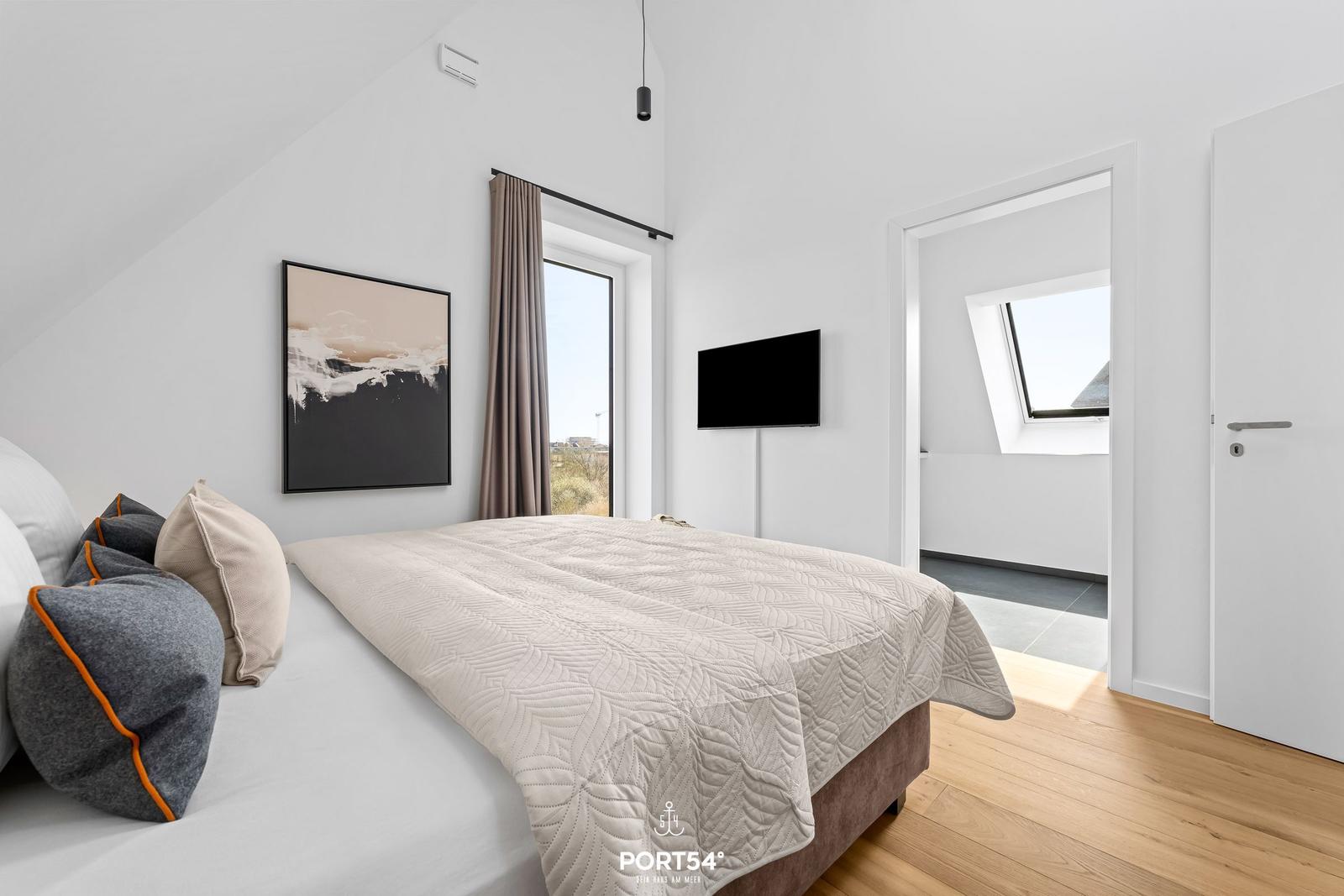 Bedroom with bed, window, wall art, and TV.