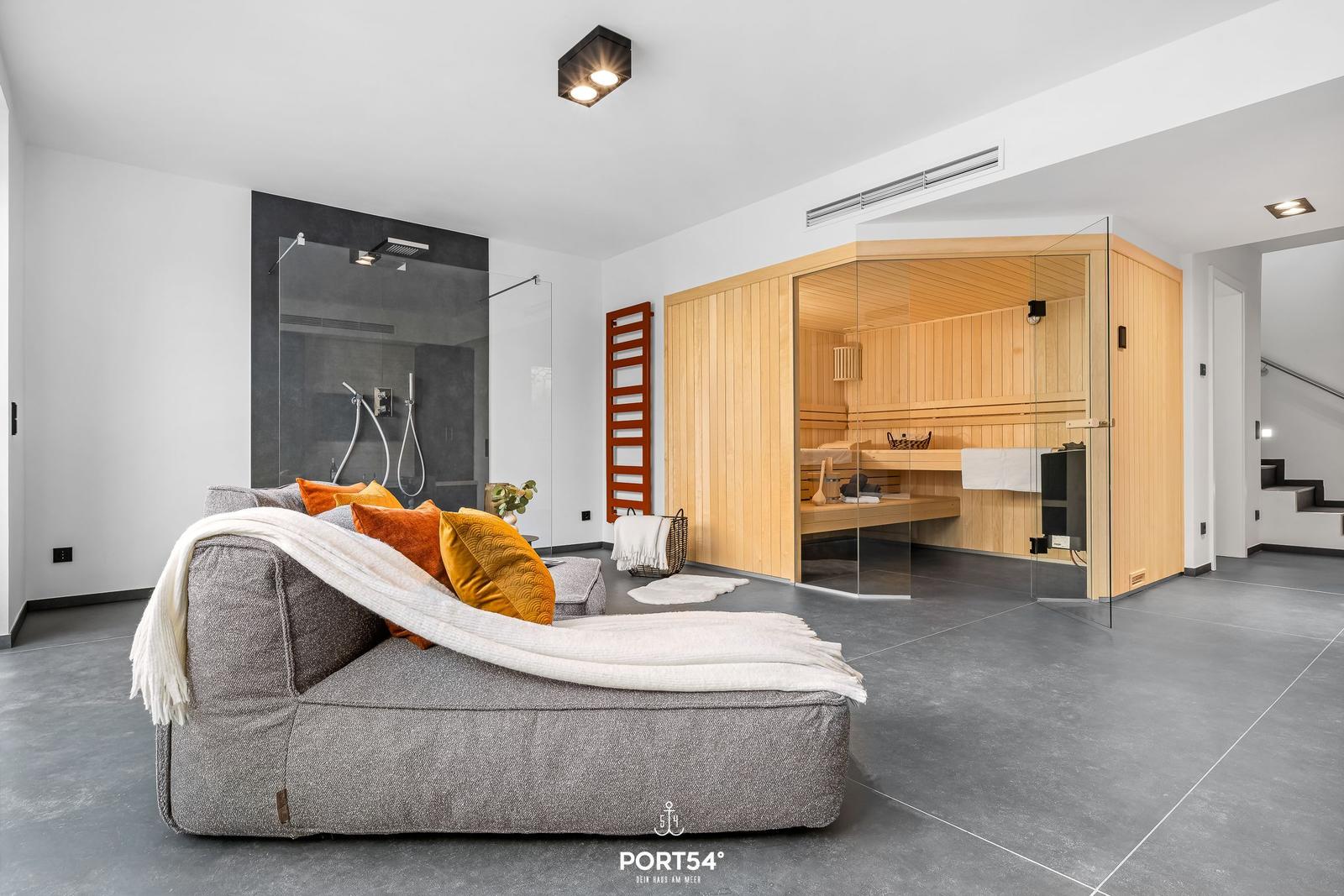 Living area with sauna and shower. Large sofa with blanket and cushions.