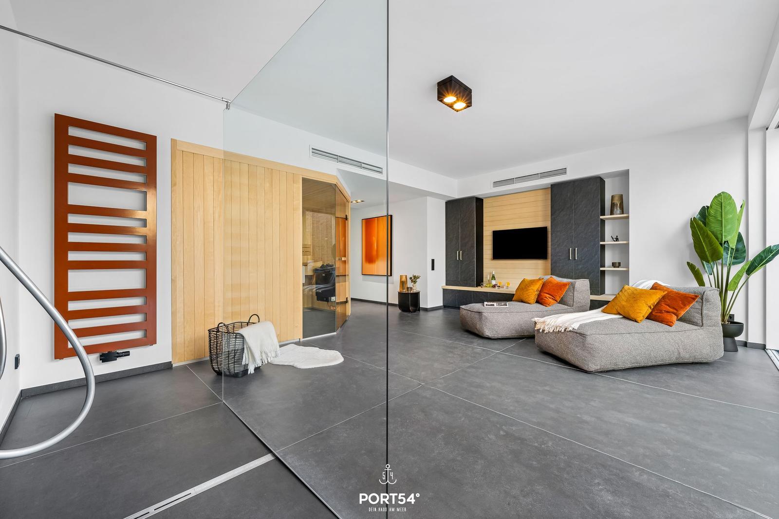 Modern living area with sofa, TV, and glass wall. Wooden doors and plants visible.