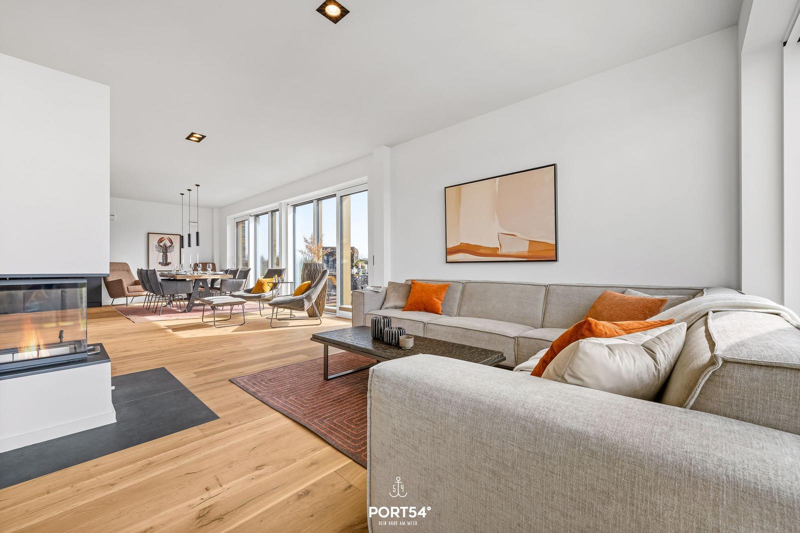 Living room with sofa, fireplace, and dining area with large windows.