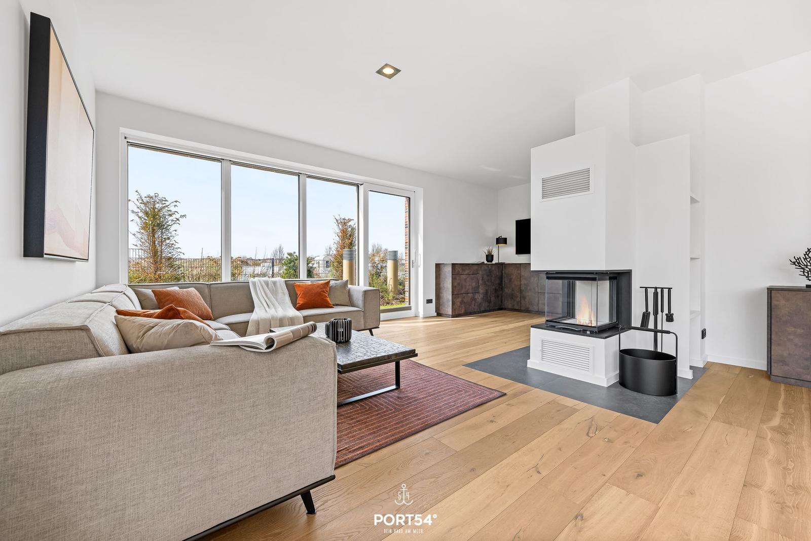 Living room with sofa, fireplace, and large windows